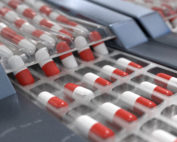 Red and white capsules in pharmaceutical production line. 3D rendered illustration.