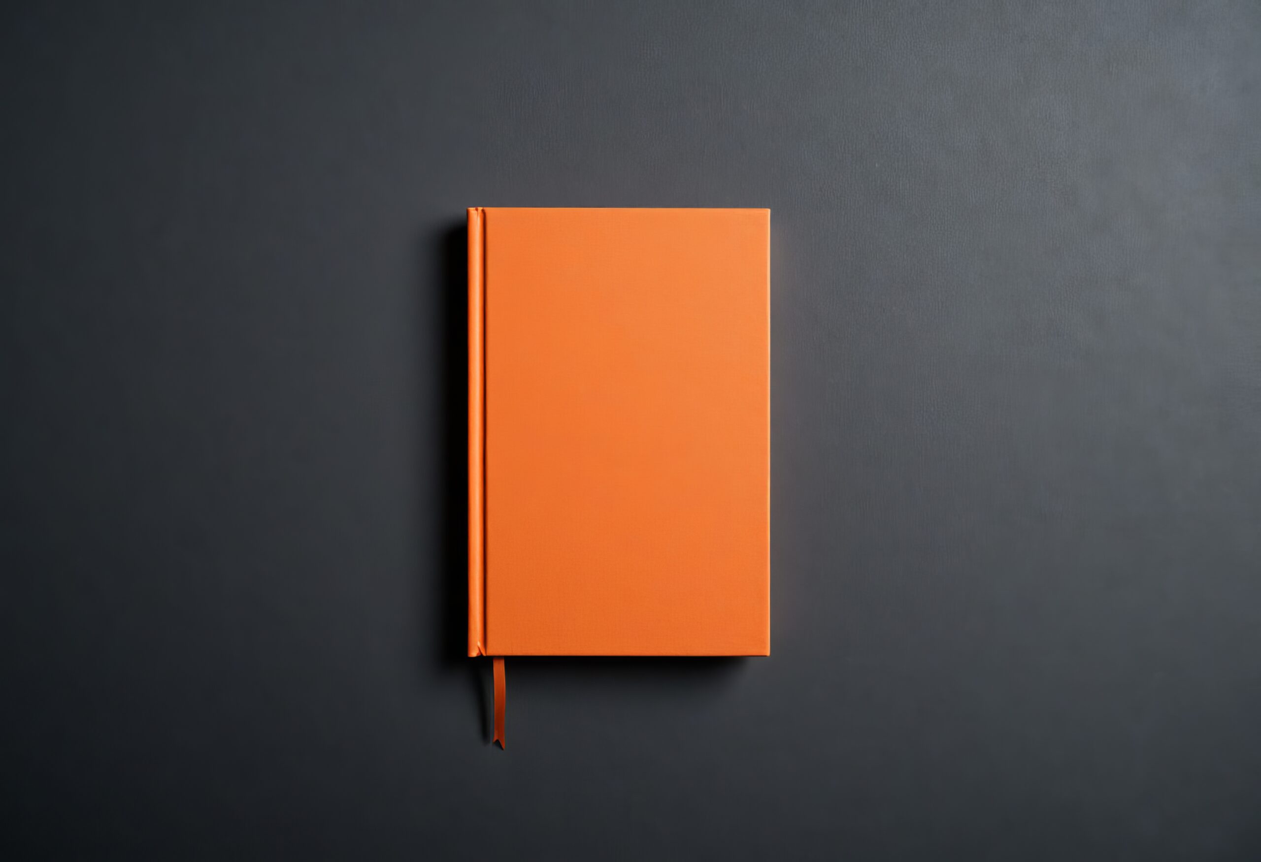 Orange book with ribbon on gray surface Orange book with ribbon on gray surface